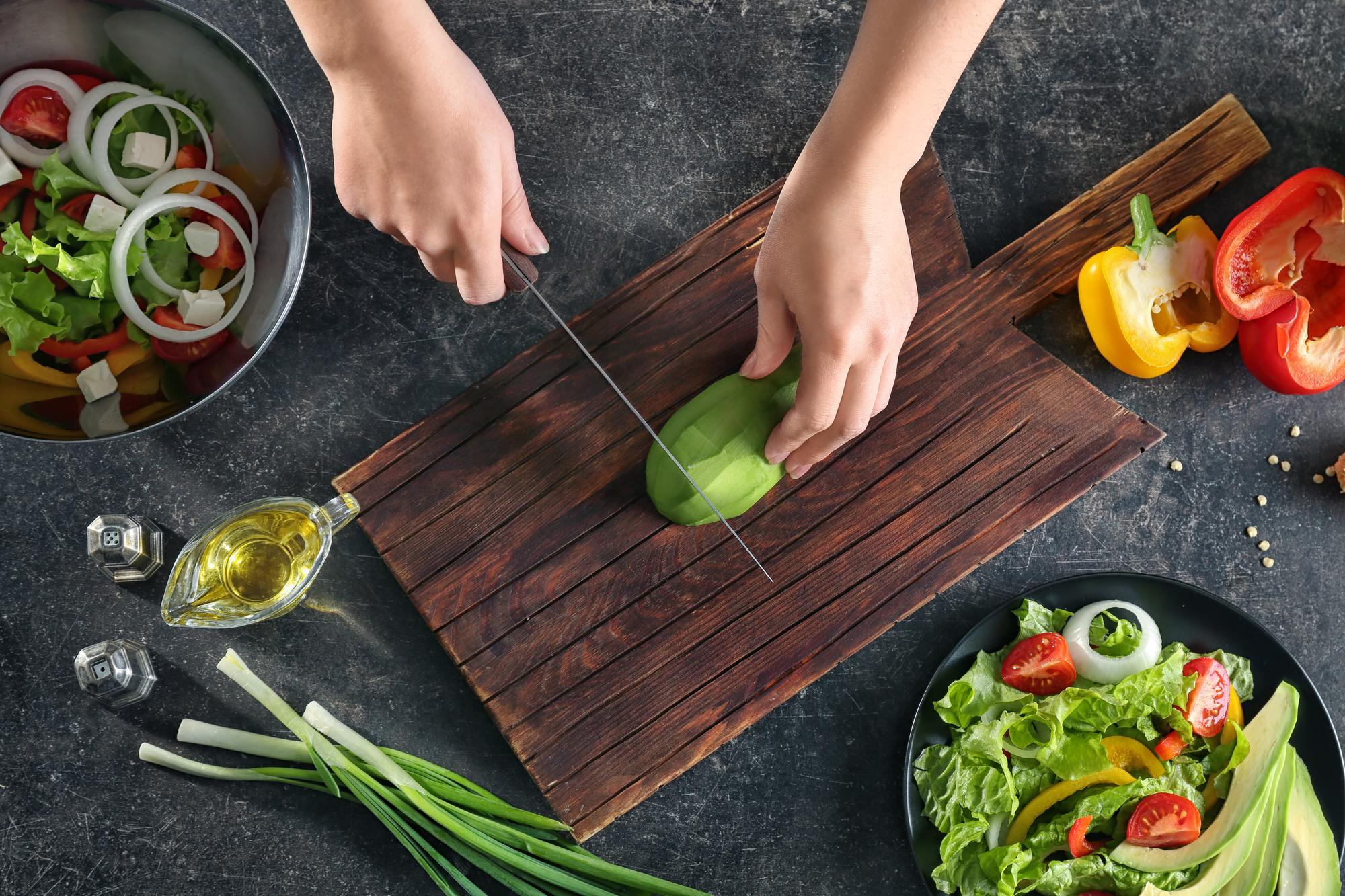 Chef slicing vegetables on wooden board