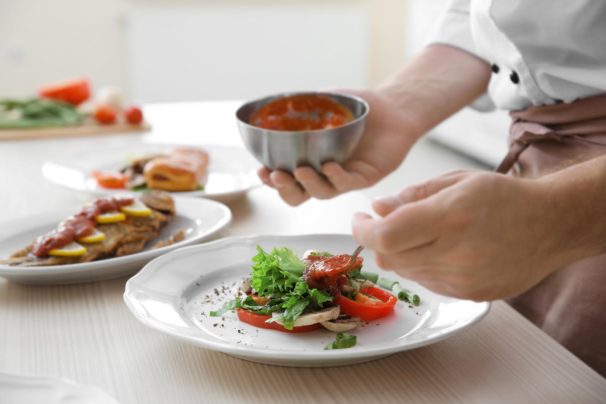Chef arranging a plated dish on wooden table